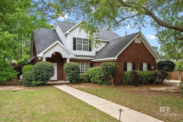 view of front of house featuring brick siding, roof with shingles, and a front lawn