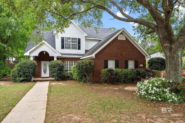 traditional-style house with brick siding, a shingled roof, and a front lawn