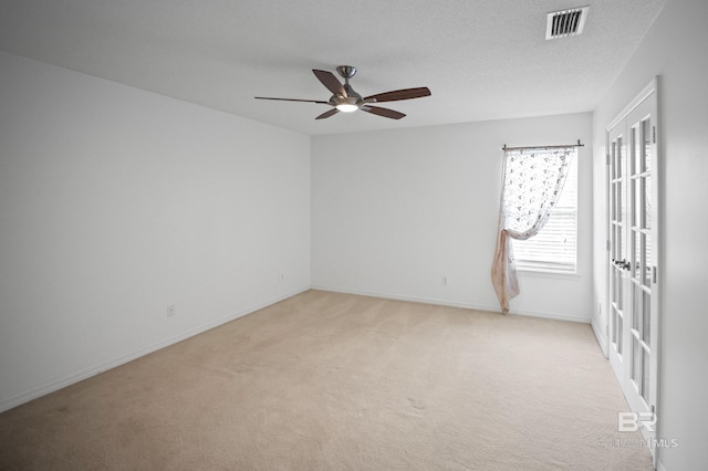 unfurnished room with a ceiling fan, baseboards, light colored carpet, and visible vents