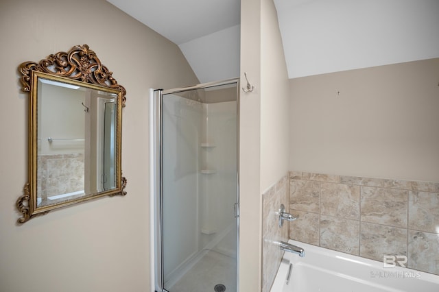 bathroom featuring vaulted ceiling, a shower stall, and a garden tub