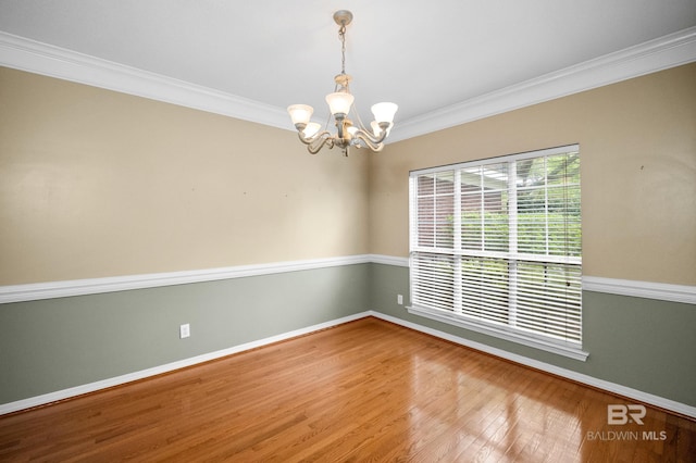 spare room with crown molding, baseboards, a chandelier, and wood finished floors