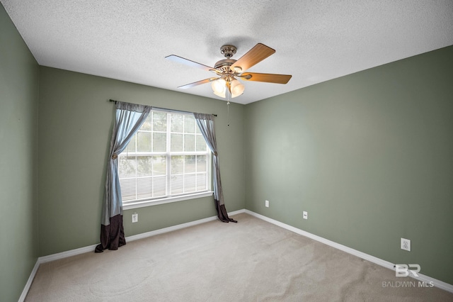 carpeted spare room featuring baseboards, a ceiling fan, and a textured ceiling