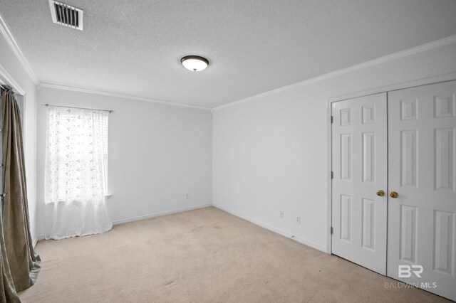 unfurnished bedroom featuring crown molding, carpet floors, a textured ceiling, baseboards, and visible vents