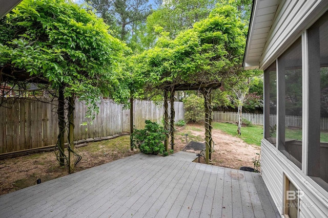 wooden deck with a fenced backyard and a sunroom