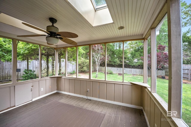 unfurnished sunroom featuring a skylight, a ceiling fan, and a healthy amount of sunlight