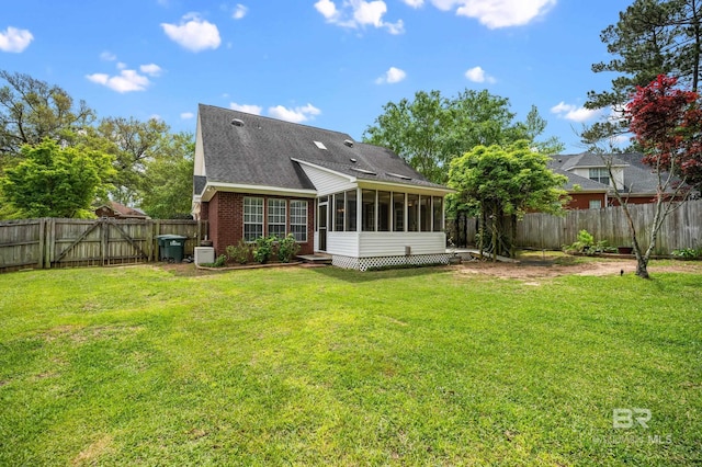 rear view of house featuring a yard, a shingled roof, a fenced backyard, and a sunroom