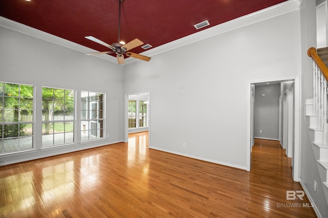 unfurnished room featuring visible vents, ornamental molding, and a towering ceiling