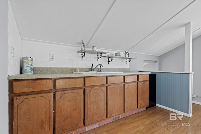 kitchen with vaulted ceiling, sink, light hardwood / wood-style flooring, and backsplash