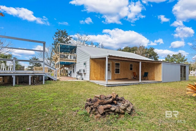 rear view of house featuring cooling unit, a lawn, and a fire pit