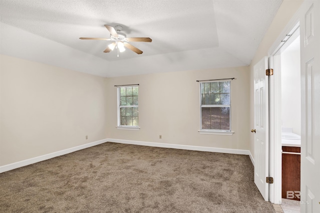 carpeted empty room with a textured ceiling, a raised ceiling, and ceiling fan