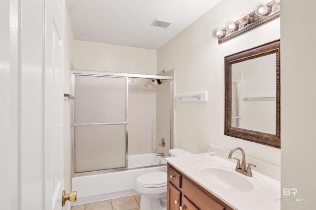 full bathroom with tile patterned floors, bath / shower combo with glass door, a textured ceiling, toilet, and vanity