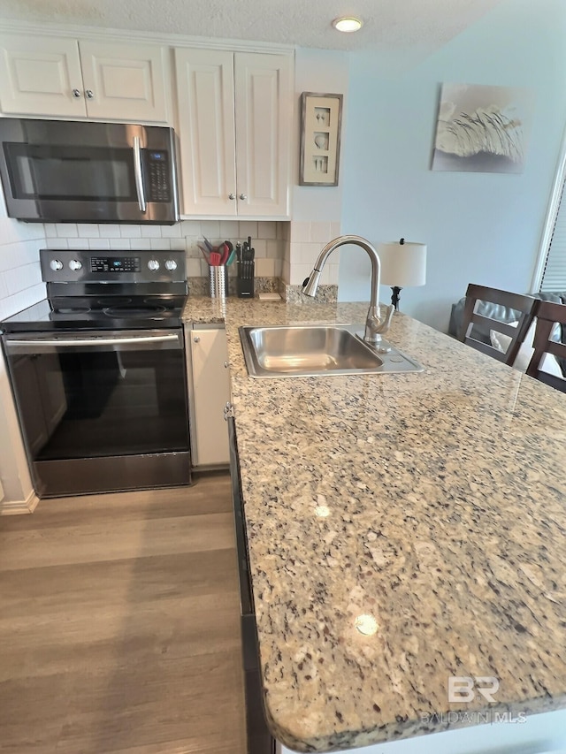 kitchen featuring white cabinets, a kitchen bar, sink, and electric range