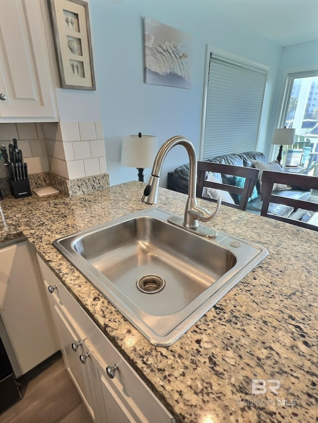 details with white cabinetry, sink, backsplash, and light stone counters