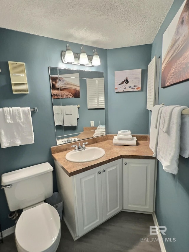 bathroom featuring hardwood / wood-style flooring, vanity, a textured ceiling, and toilet