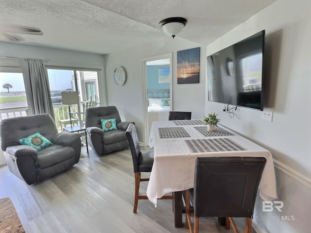 dining area with light hardwood / wood-style floors and a textured ceiling