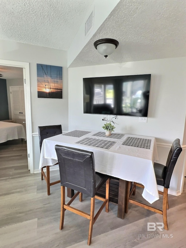 dining room with a textured ceiling and light wood-type flooring