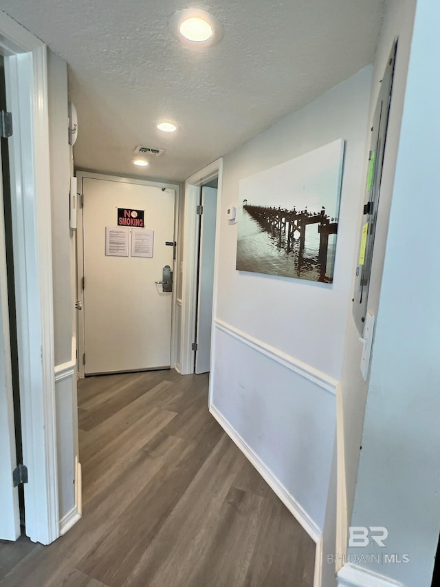 hall featuring a textured ceiling and dark hardwood / wood-style flooring