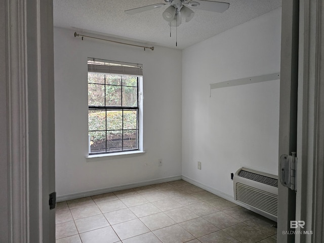 unfurnished room featuring ceiling fan, an AC wall unit, a textured ceiling, and light tile patterned floors