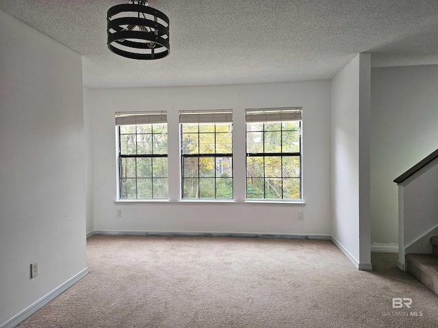 carpeted spare room with a textured ceiling and a wealth of natural light