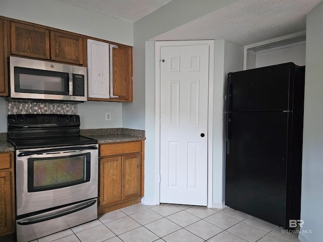 kitchen with light tile patterned floors, a textured ceiling, and stainless steel appliances