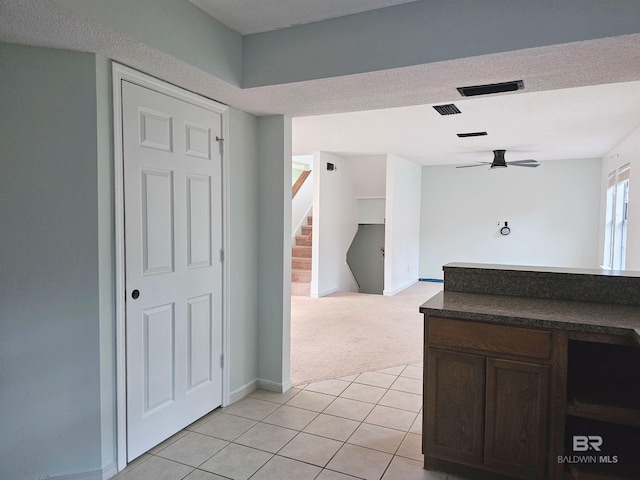 kitchen featuring ceiling fan, dark brown cabinets, light tile patterned floors, and a textured ceiling