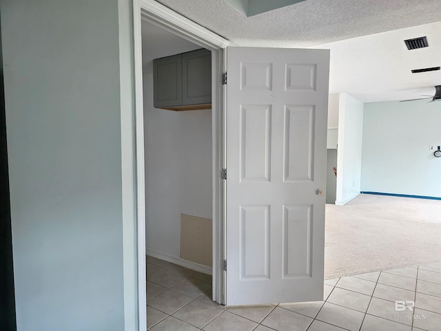 hallway featuring a textured ceiling and light carpet