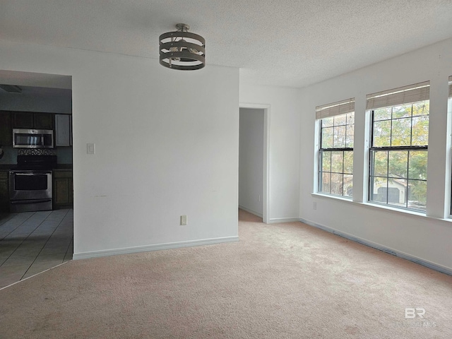 spare room with a chandelier, a textured ceiling, and light colored carpet