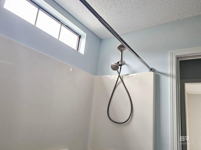 room details featuring a shower and a textured ceiling