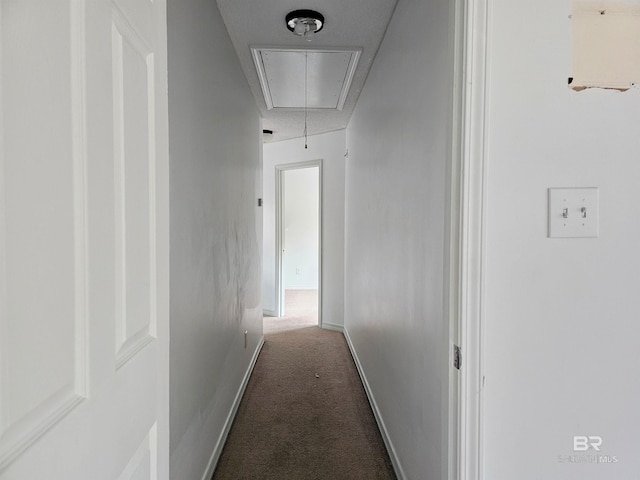 corridor with a textured ceiling and dark colored carpet