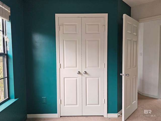 unfurnished bedroom with a closet, multiple windows, and light colored carpet