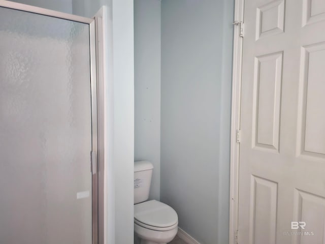 bathroom with toilet and a shower with door