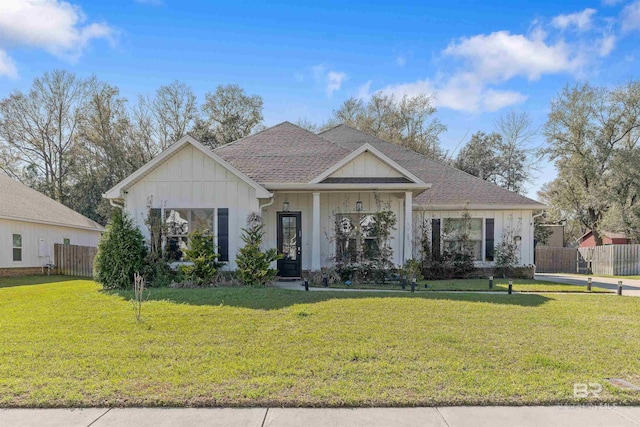 view of front of home with board and batten siding, a front yard, and fence
