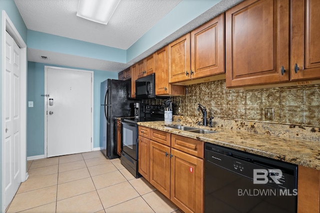 kitchen with backsplash, light stone countertops, light tile patterned flooring, black appliances, and a sink