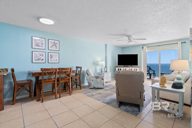 living room with light tile patterned floors, baseboards, a textured ceiling, and ceiling fan