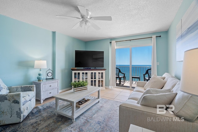 living room featuring a textured ceiling, tile patterned floors, baseboards, and ceiling fan