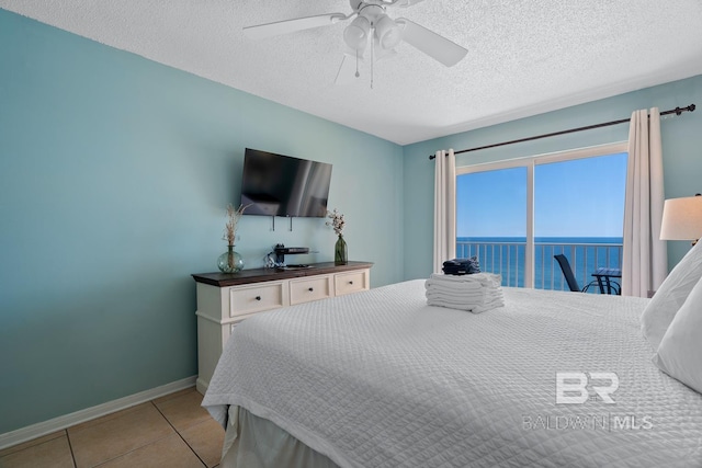 tiled bedroom featuring a textured ceiling, baseboards, and a ceiling fan