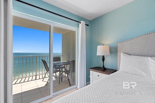 bedroom with tile patterned flooring, access to exterior, a view of the beach, and a water view