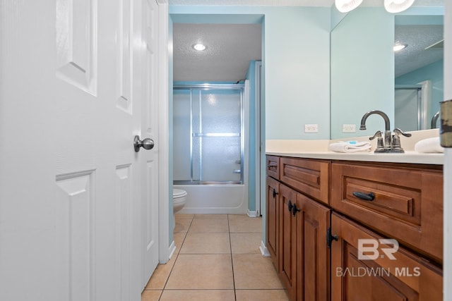 bathroom with toilet, vanity, tile patterned floors, combined bath / shower with glass door, and a textured ceiling