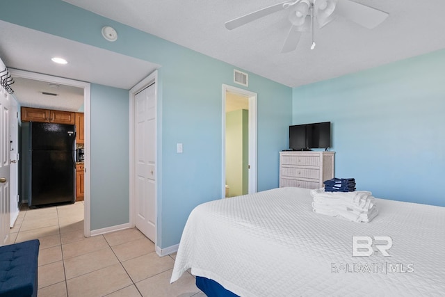 bedroom featuring baseboards, visible vents, light tile patterned flooring, freestanding refrigerator, and a closet