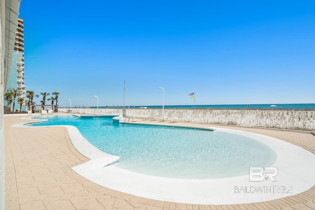 pool with a patio area and a water view