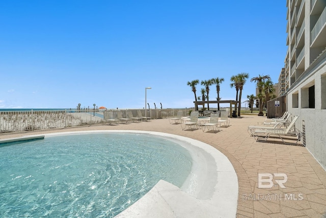 community pool with a patio and fence