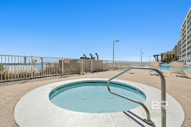 view of swimming pool featuring a patio area, a community hot tub, and fence