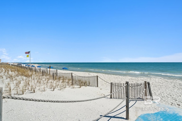 property view of water with fence and a beach view