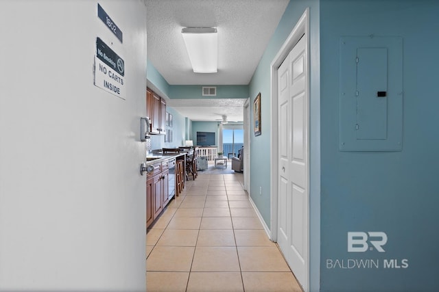 kitchen with visible vents, brown cabinets, electric panel, a textured ceiling, and light tile patterned floors