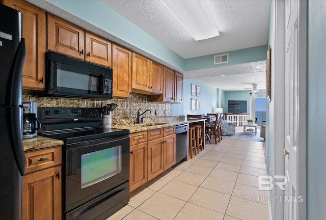 kitchen featuring visible vents, black appliances, a ceiling fan, a sink, and light tile patterned floors