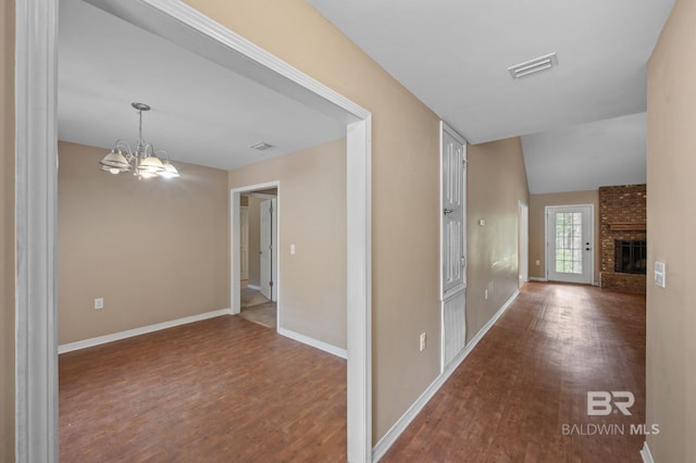 hallway featuring wood finished floors, a chandelier, and baseboards