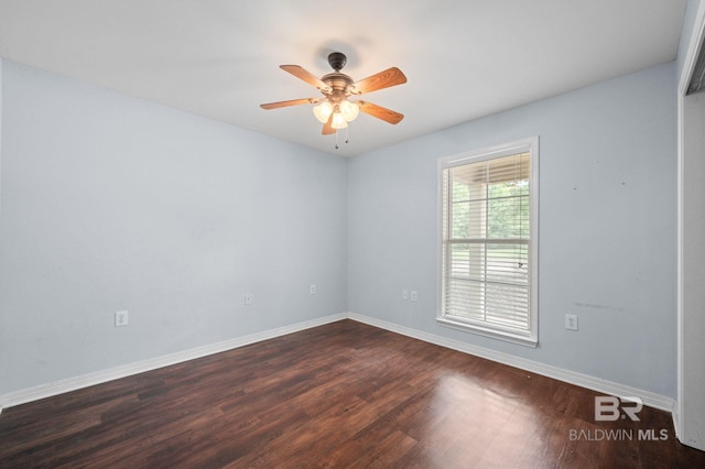 unfurnished room with dark wood finished floors, a ceiling fan, and baseboards