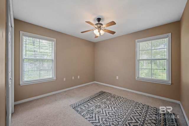 carpeted empty room featuring healthy amount of natural light, a ceiling fan, and baseboards