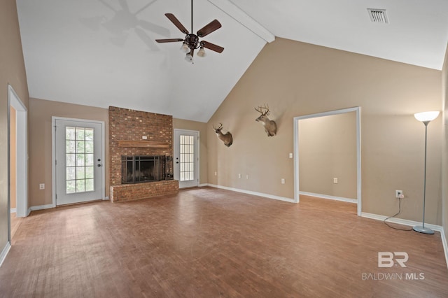 unfurnished living room featuring a ceiling fan, beam ceiling, wood finished floors, high vaulted ceiling, and a brick fireplace