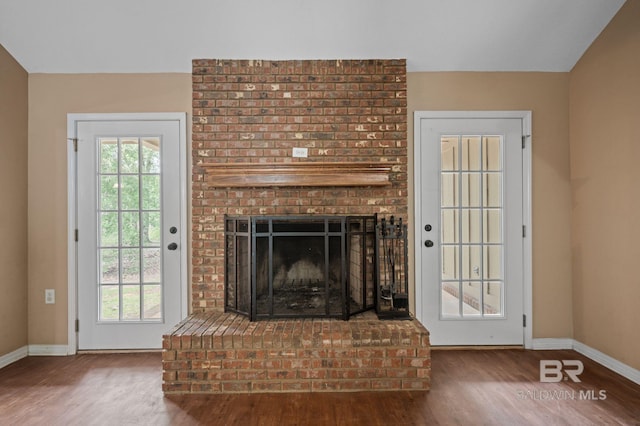 unfurnished living room with wood finished floors, baseboards, and a fireplace